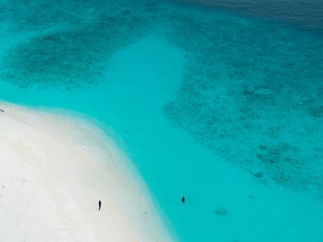 Aerial view of the pristine white sands meeting the turquoise waters where tiny figures dot the landscape Hoarafushi Thiladhunmathee Uthuruburi Maldives. Aerial view of the pristine white sands meeting the turquoise waters where tiny figures dot the landscape Hoarafushi Thiladhunmathee Uthuruburi Maldives.