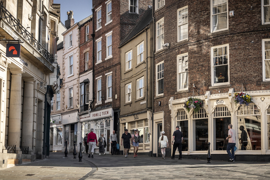 Durham United Kingdom 13 July 2026 View of a historic street in Durham featuring traditional brick buildings storefronts and pedestrians walking along the paved road. Durham United Kingdom 13 July 2026 View of a historic street in Durham featuring traditional brick buildings storefronts and pedestrians walking along the paved road.
