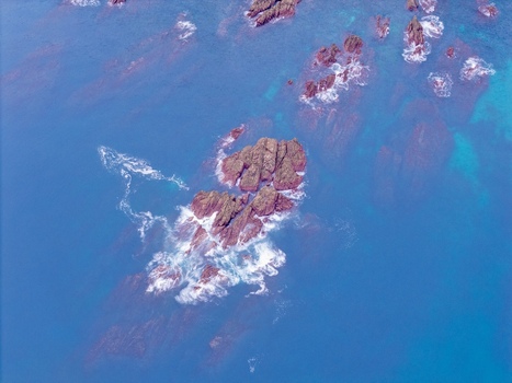 Aerial view of jagged rocky formations and islets surrounded by deep blue sea water and white foam near the coast of Cudillero Asturias Spain. Aerial view of jagged rocky formations and islets surrounded by deep blue sea water and white foam near the coast of Cudillero Asturias Spain.