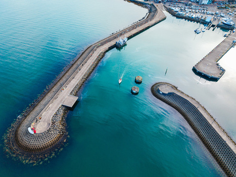 Aerial view of Bangor Harbour and Town with its distinctive breakwater turquoise water and small boat navigating the marina in Bangor Northern Ireland United Kingdom.