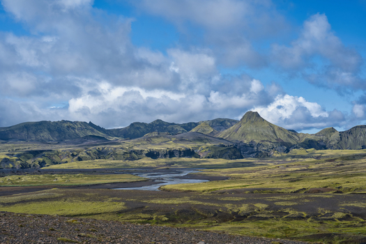 View of the volcanic landscape of Laki with moss covered lava fields a winding river and distant mountains in Kirkjubaejarklaustur Skaftarhreppur Iceland. View of the volcanic landscape of Laki with moss covered lava fields a winding river and distant mountains in Kirkjubaejarklaustur Skaftarhreppur Iceland.