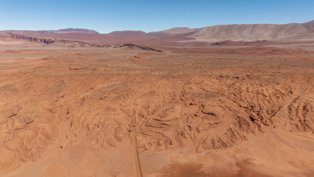 Aerial view of the arid red hued desert landscape of Tolar Grande featuring winding dirt roads cutting through rugged terrain in Tolar Grande Salta Province Argentina. Aerial view of the arid red hued desert landscape of Tolar Grande featuring winding dirt roads cutting through rugged terrain in Tolar Grande Salta Province Argentina.