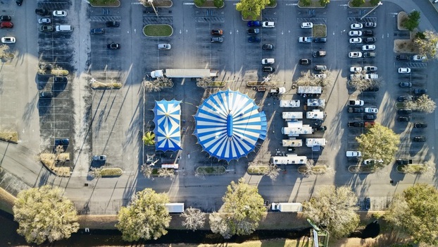 Aerial view of a blue and white striped circus tent standing out in a parking lot surrounded by vehicles St. Augustine Florida United States. Aerial view of a blue and white striped circus tent standing out in a parking lot surrounded by vehicles St. Augustine Florida United States.