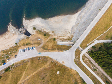 Aerial view of Belmeken Dam showing the concrete dam wall a parking area with parked cars and the shoreline of the reservoir surrounded by grassy slopes in Pazardzhik Bulgaria. Aerial view of Belmeken Dam showing the concrete dam wall a parking area with parked cars and the shoreline of the reservoir surrounded by grassy slopes in Pazardzhik Bulgaria.