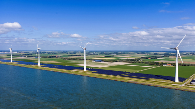 Aerial view of wind turbines and solar panels along the waterfront in the green agricultural landscape of Rutten Flevoland Netherlands. Aerial view of wind turbines and solar panels along the waterfront in the green agricultural landscape of Rutten Flevoland Netherlands.