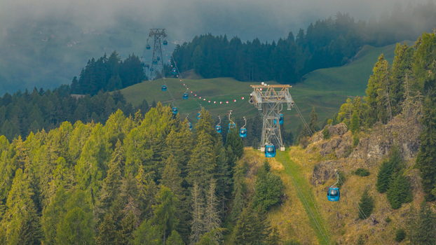 Compatsch Italy 18 September 2026 Aerial view of the Alpe di Siusi cable car line crossing forested alpine slopes beneath low clouds in the Dolomites. Compatsch Italy 18 September 2026 Aerial view of the Alpe di Siusi cable car line crossing forested alpine slopes beneath low clouds in the Dolomites.