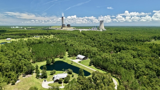 Aerial view of the Seminole Electric power plant with its cooling towers and chimneys rising above the surrounding dense forest and rural landscape in Palatka Florida United States.