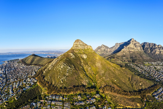 Aerial view of Lion s Head mountain rising above the residential suburbs and coastal landscape of Cape Town Western Cape South Africa.