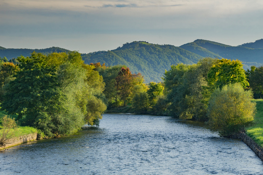 Aerial view of the Hron river flowing through the lush green landscape with rolling hills and trees under a soft sky in Sliac Banska Bystrica Region Slovakia.