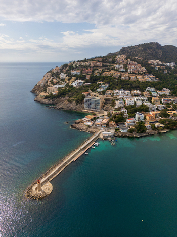 Aerial view of the lighthouse at the end of a long pier turquoise waters and hillside villas in the coastal town of Port d Andratx Balearic Islands Spain. Aerial view of the lighthouse at the end of a long pier turquoise waters and hillside villas in the coastal town of Port d Andratx Balearic Islands Spain.