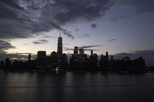 Aerial view of the New York skyline at twilight with illuminated skyscrapers reflecting over the Hudson River in New York New York United States.