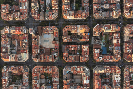 Aerial view of the Eixample district in Barcelona featuring the iconic grid layout of city blocks with terracotta rooftops courtyards and narrow streets in Barcelona Catalonia Spain. Aerial view of the Eixample district in Barcelona featuring the iconic grid layout of city blocks with terracotta rooftops courtyards and narrow streets in Barcelona Catalonia Spain.