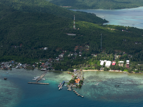 Aerial view of the harbor with its piers jutting into the turquoise sea against the backdrop of the lush green island Karimunjawa Jawa Tengah Indonesia. Aerial view of the harbor with its piers jutting into the turquoise sea against the backdrop of the lush green island Karimunjawa Jawa Tengah Indonesia.