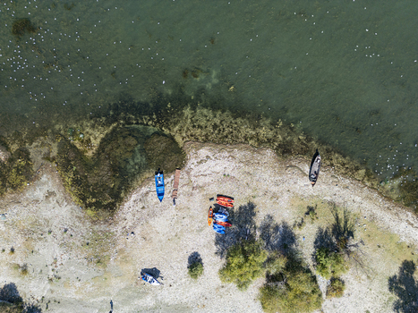 Aerial view of the Moloja Shiroke shoreline on Lake Shkodra with colorful kayaks and small boats resting on the pebbled beach in Shkoder Qarku i Shkodres Albania. Aerial view of the Moloja Shiroke shoreline on Lake Shkodra with colorful kayaks and small boats resting on the pebbled beach in Shkoder Qarku i Shkodres Albania.