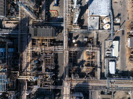 Aerial view of an industrial oil refinery complex featuring a dense network of pipes storage tanks and processing structures in Carson California United States.
