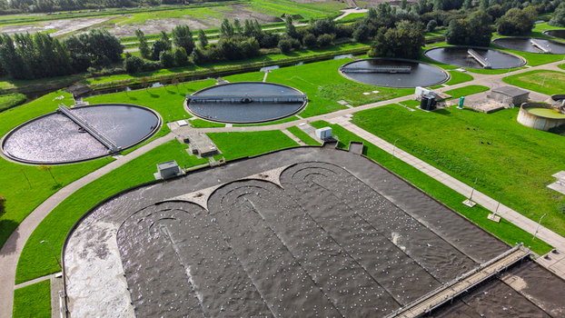 Aerial view of a wastewater treatment plant with circular sedimentation tanks and aeration basins surrounded by green grass in Warmenhuizen North Holland Netherlands. Aerial view of a wastewater treatment plant with circular sedimentation tanks and aeration basins surrounded by green grass in Warmenhuizen North Holland Netherlands.