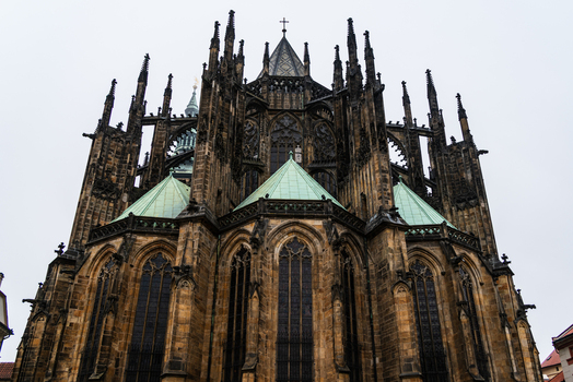 View of the intricate Gothic architecture of St. Vitus Cathedral with its stone walls green copper roofs and stained glass windows Prague Prague Czechia.