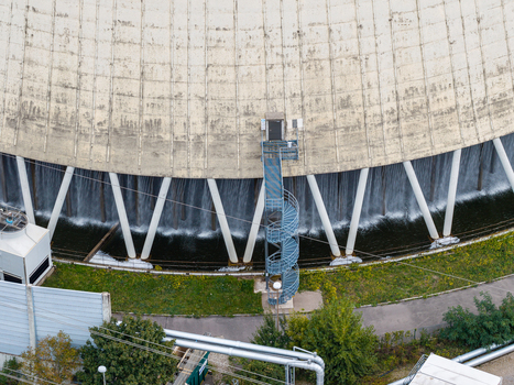 Aerial view of the cooling tower at Heizkraftwerk Reuter West with water cascading down the base and a blue spiral staircase in Berlin Berlin Germany.