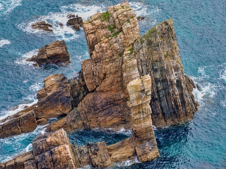 Aerial view of the jagged rock formations at Silence Beach Viewpoint with turquoise water and crashing waves in Cudillero Asturias Spain.