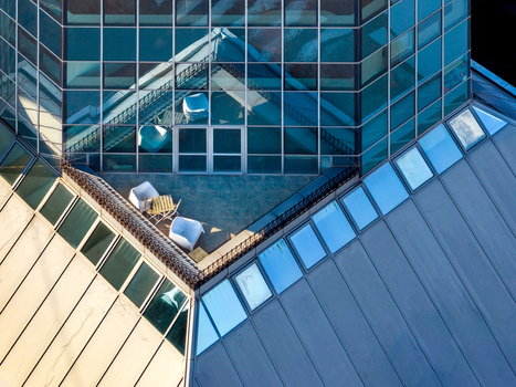 Aerial view of a modern building rooftop terrace with white chairs and a small table featuring glass facades and metal roofing in Belgrade City of Belgrade Serbia. Aerial view of a modern building rooftop terrace with white chairs and a small table featuring glass facades and metal roofing in Belgrade City of Belgrade Serbia.