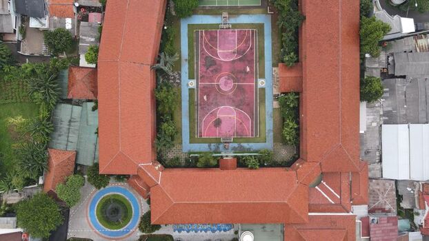 Aerial view of Pondok Labu school courtyard featuring a basketball court surrounded by red tile roofs in Cilandak Jakarta Indonesia. Aerial view of Pondok Labu school courtyard featuring a basketball court surrounded by red tile roofs in Cilandak Jakarta Indonesia.