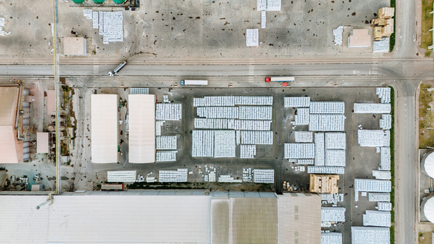 Aerial view of organized white pallets in an industrial warehouse yard with trucks and large factory buildings in Sabac Vojvodina Serbia. Aerial view of organized white pallets in an industrial warehouse yard with trucks and large factory buildings in Sabac Vojvodina Serbia.