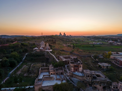 Aerial view of Katas Raj Temple Complex featuring ancient stone structures and courtyards surrounded by rural landscape and fields under a soft sunset sky in Katas Punjab Pakistan. Aerial view of Katas Raj Temple Complex featuring ancient stone structures and courtyards surrounded by rural landscape and fields under a soft sunset sky in Katas Punjab Pakistan.
