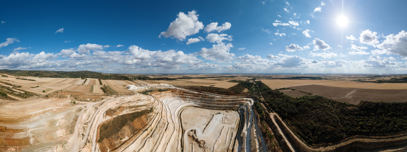 Aerial view of the open pit quarry surrounded by agricultural fields and forests under a bright blue sky in Besenovo Vojvodina Serbia.