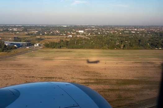 Aerial view of the earth with a dark shadow cast across the vast open field buildings and scattered trees fade into the horizon Warsaw Masovian Voivodeship Poland. Aerial view of the earth with a dark shadow cast across the vast open field buildings and scattered trees fade into the horizon Warsaw Masovian Voivodeship Poland.