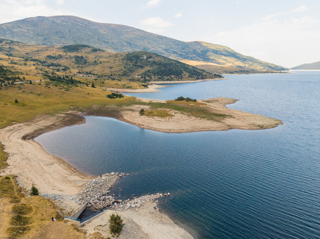 Aerial view of Belmeken Reservoir with its blue water surrounding grassy hills and rugged mountain landscape in Pazardzhik Bulgaria. Aerial view of Belmeken Reservoir with its blue water surrounding grassy hills and rugged mountain landscape in Pazardzhik Bulgaria.