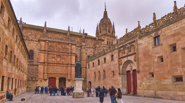 Salamanca Spain 29 November 2025 View of the ornate Plateresque facade of the University of Salamanca with the statue of Fray Luis de Leon and tourists in the historic square.