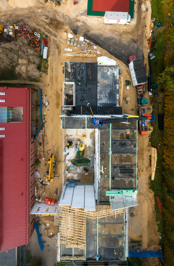 Aerial view of a construction site showing building foundations wooden roof trusses construction materials and heavy machinery in Latvia. Aerial view of a construction site showing building foundations wooden roof trusses construction materials and heavy machinery in Latvia.