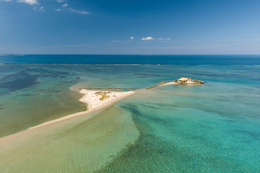 Aerial view of a small island with a church and a sandy spit surrounded by turquoise waters in Lefkada Greece.