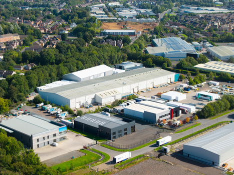 Aerial view of an industrial park with large warehouses storage yards trucks and surrounding green trees in Lisburn Northern Ireland United Kingdom. Aerial view of an industrial park with large warehouses storage yards trucks and surrounding green trees in Lisburn Northern Ireland United Kingdom.