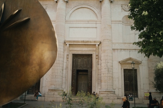 View of the neoclassical facade of Palazzo della Gran Guardia with a large bronze sculpture and people sitting on the steps in Verona Veneto Italy.