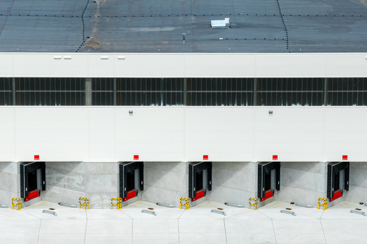 Aerial view of a modern industrial warehouse featuring multiple loading docks with red levelers and concrete walls in Poland.