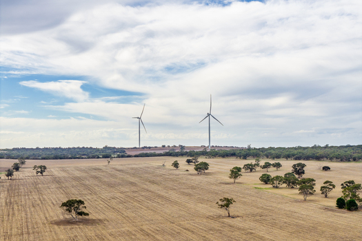 Aerial view of wind turbines standing in dry rural fields with scattered trees under a cloudy sky in Nhill Victoria Australia. Aerial view of wind turbines standing in dry rural fields with scattered trees under a cloudy sky in Nhill Victoria Australia.