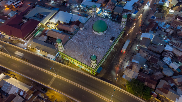 Aerial view of the illuminated Tamale Central Mosque with its green dome and minarets situated next to a busy highway with light trails from traffic in Tamale Northern Region Ghana. Aerial view of the illuminated Tamale Central Mosque with its green dome and minarets situated next to a busy highway with light trails from traffic in Tamale Northern Region Ghana.