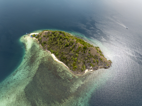 Aerial view of Pulau Kelor island surrounded by turquoise coral reefs and deep blue sea in Komodo East Nusa Tenggara Indonesia.
