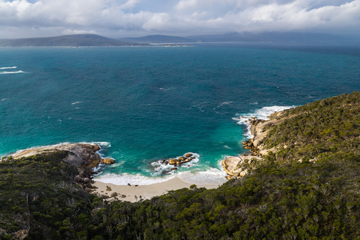 Aerial view of Two Peoples Bay Nature Reserve featuring a secluded sandy beach turquoise waters and rocky coastline surrounded by native vegetation in Albany Western Australia Australia.
