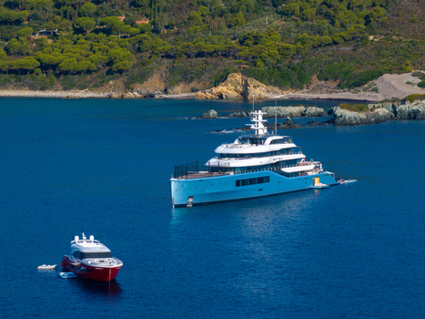 Aerial view of the luxury yacht Netto II anchored in the deep blue waters of Lacona Bay surrounded by lush green Mediterranean hills and rocky coastline in Lacona Tuscany Italy.
