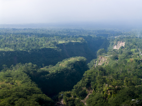 Aerial view of Tambang Pasir Merapi Kali Gendol Sand Mine surrounded by dense tropical forest and steep cliffs under a hazy sky Kecamatan Cangkringan Daerah Istimewa Yogya Indonesia. Aerial view of Tambang Pasir Merapi Kali Gendol Sand Mine surrounded by dense tropical forest and steep cliffs under a hazy sky Kecamatan Cangkringan Daerah Istimewa Yogya Indonesia.