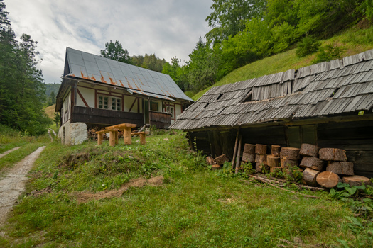 View of rustic wooden houses nestled amidst lush green hills and cloudy skies a quaint scene evoking tranquility and history Velka Fatra Banska Bystrica Region Slovakia. View of rustic wooden houses nestled amidst lush green hills and cloudy skies a quaint scene evoking tranquility and history Velka Fatra Banska Bystrica Region Slovakia.