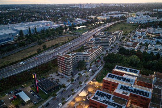 Aerial view of the Brain Box Campus in Adlershof featuring modern office buildings with green roofs adjacent to a highway and urban landscape in Berlin Berlin Germany. Aerial view of the Brain Box Campus in Adlershof featuring modern office buildings with green roofs adjacent to a highway and urban landscape in Berlin Berlin Germany.