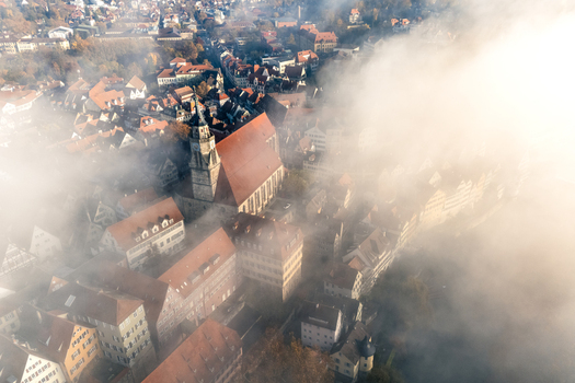 Aerial view of the Stiftskirche church and historic red tiled rooftops partially shrouded in thick morning fog in Tubingen Baden Wurttemberg Germany. Aerial view of the Stiftskirche church and historic red tiled rooftops partially shrouded in thick morning fog in Tubingen Baden Wurttemberg Germany.