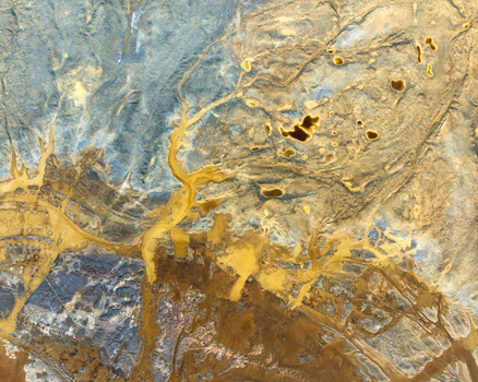 Aerial view of the abstract textures and vibrant yellow mineral deposits in the open pit mining landscape of Minas de Riotinto Andalusia Spain.