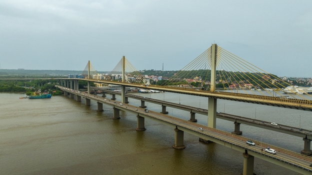 Aerial view of the Atal Setu Goa cable stayed bridge spanning the Mandovi River with traffic flowing across the structure under a cloudy sky in Panaji Goa India.