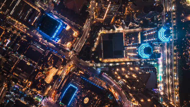 Aerial view of the illuminated Jakarta skyline at night featuring modern skyscrapers with blue lighting busy roads and dense urban infrastructure. Jakarta Indonesia.