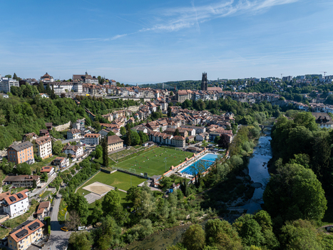 Aerial view of St Nicolas Cathedral a sports field and a swimming pool by the Sarine river in Fribourg Fribourg Switzerland. Aerial view of St Nicolas Cathedral a sports field and a swimming pool by the Sarine river in Fribourg Fribourg Switzerland.