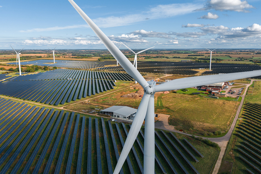 Aerial view of Chelveston Renewable Energy BESS featuring a large wind turbine and extensive solar panel arrays across the landscape in Chelveston England United Kingdom. Aerial view of Chelveston Renewable Energy BESS featuring a large wind turbine and extensive solar panel arrays across the landscape in Chelveston England United Kingdom.